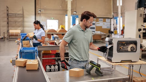 Man pulling label from RFID printer on manufacturing plant floor